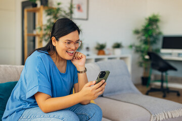 A young woman showcases a heartfelt reaction while engaging on a video call, surrounded by a beautifully decorated cozy space with modern accents.