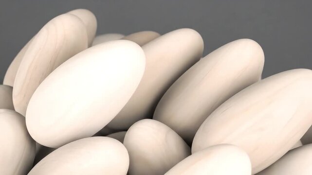 Close-up of pale wooden objects, smooth and cylindrical, slightly curved, on a gradient gray background