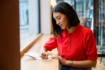 Young woman writing notes planning agenda in cafe