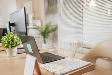 Home office workspace business desk setup provides laptop computer monitor documents calendar green plants creating efficient productive environment for remote work