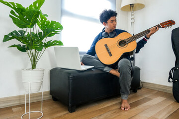 Young Musician Composes Music At Home With Guitar And Laptop
