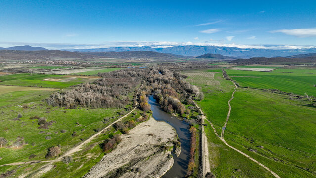 A landscape of a river flowing through a forest with mountain view.