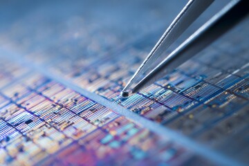 Tweezers carefully manipulate a tiny component on a complex semiconductor wafer, showing advanced microelectronic technology and intricate circuit patterns.