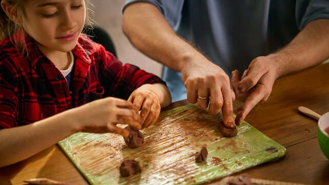 Child and father shaping clay together on homework board. Concept of hands-on learning, creative skill development, DIY craft tutorials, and practical family education projects.