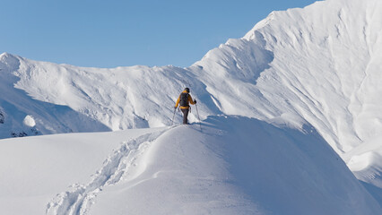 Aerial photo of a ski mountaineer ascending a snowy alpine ridge in Austria. Winter landscape,...