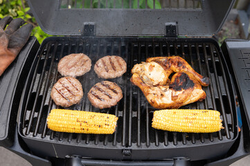Grilled burgers, chicken, and corn on barbecue grill