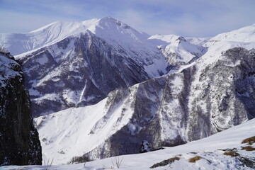 A snow-covered mountain range in the Caucasus region near the Gudauri ski resort. Georgia. Snow-capped mountain peaks and steep slopes.