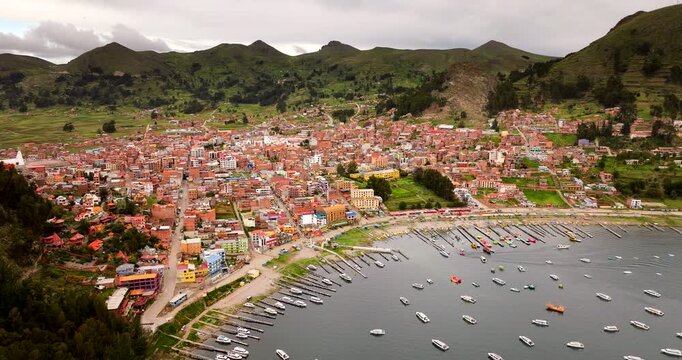 Aerial drone view Copacabana town on shore of Lake Titicaca, Bolivia, harbor with boats and surrounding green hills