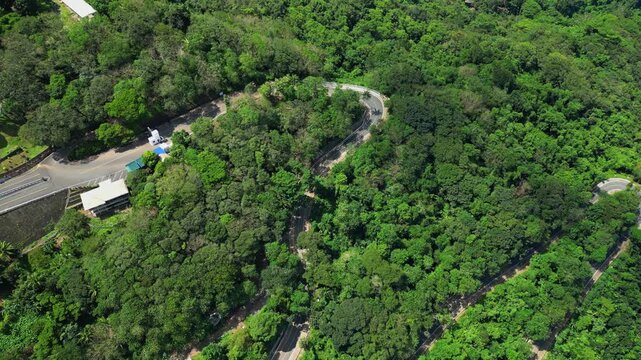 Tilt‑down aerial revealing a winding road through the dense forested slopes of Mt. Samat National Shrine, framed by greenery and hillside terrain in Pilar, Bataan, Philippines.
