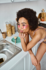Relaxing at home, young woman enjoys self care in her cozy kitchen space while daydreaming