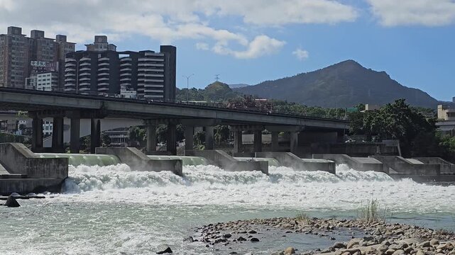 Taipei City, Taiwan. November 15, 2025. Xindian River weir with distant mountains and urban riverside landscape creating a balanced eco scene of nature and city