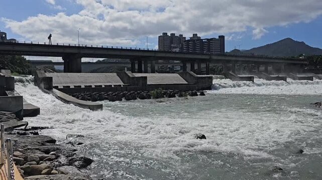 Taipei City, Taiwan. November 15, 2025. Xindian River weir with distant mountains and urban riverside landscape creating a balanced eco scene of nature and city
