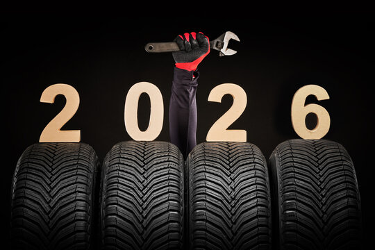 Fototapeta Winter car tires service and thumbs up hands of mechanic and text 2026 happy new year on black background