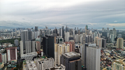 Stunning high angle drone view of Makati City, the main business district of Metro Manila, Philippines. Tall modern skyscrapers and dense high-rise condominiums dominate the skyline.