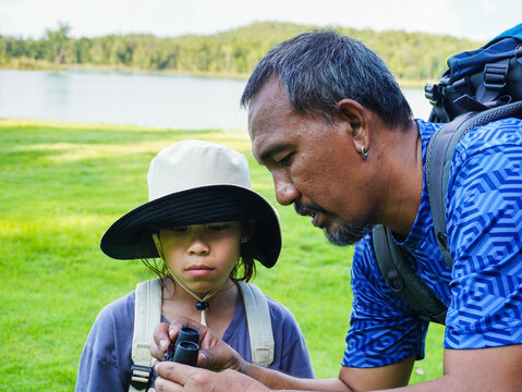 Father Teaching Daughter to Use Binoculars for Bird Watching or Nature Exploration.