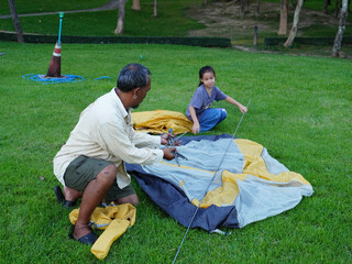 Father and Daughter Setting Up Camping Tent Together on Green Grass.