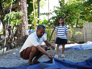 Father and Daughter Working Together to Pack Up Camping Tent.
