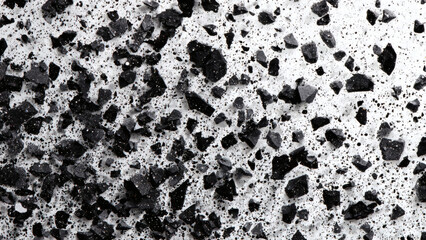Detailed close-up of a textured surface with sharp black granules embedded in a light concrete background, creating a monochrome abstract pattern