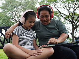 Mother and Daughter Relaxing on Park Bench with Music and Smartphone