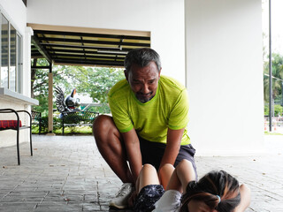 Father and daughter doing sit-ups together outdoors