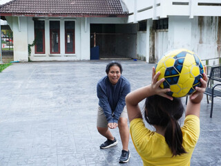 Mother and Daughter Playing Volleyball and Passing Ball Outdoors with Fun