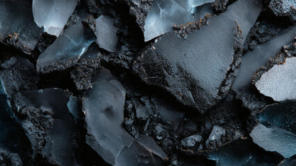 Conceptual abstract background of shattered black stone, featuring the raw, rugged texture of crushed coal or charcoal