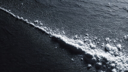 A line of white powder on a dark surface, symbolizing substance or concept