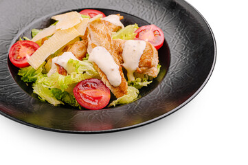 Tasty chicken salad with tomatoes and creamy dressing on black plate