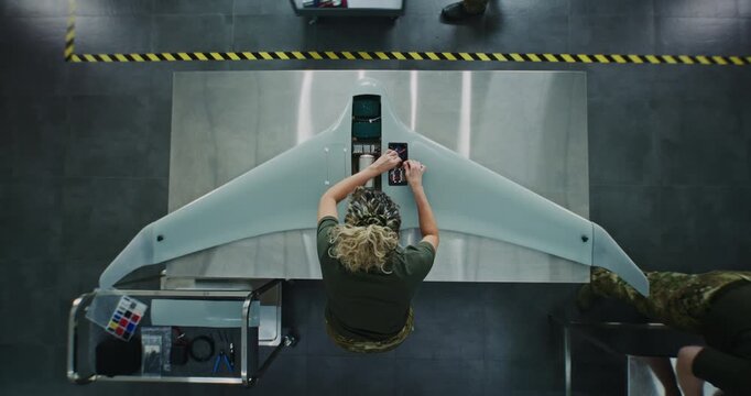 Woman in Camouflage Uniform Working on Next Generation Drone. Female Soldier Installing Electronic Parts Into Surveillance Drone. Concept of Advanced Military Research and Development. Top View.