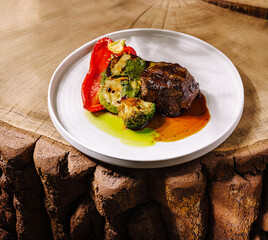 Delicious steak served with zucchini and red bell pepper on rustic table