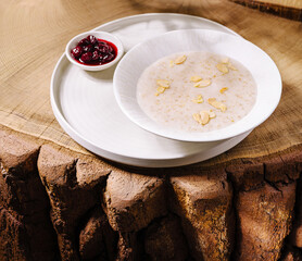 Warm bowl of oatmeal with toasted almonds and cherry compote on a wooden table