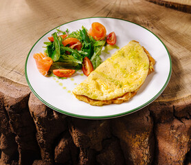Delicious omelette served with fresh salad and smoked salmon on rustic wood