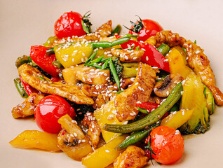 Colorful stir-fried vegetables and chicken served on a beige plate