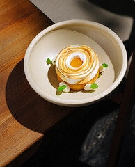 Delicate dessert with creamy topping and mint leaves on a wooden table