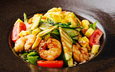 Fresh shrimp salad with mango and vegetables in a dark bowl