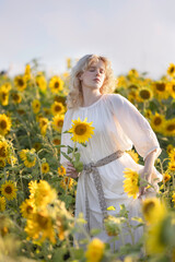 Beautiful blonde girl in a white dress in a field of sunflowers
