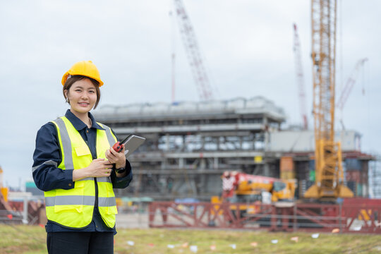 Working at a busy industry port, the Asian female engineer analyzes transport data to improve workflow efficiency and support the team in achieving project goals.