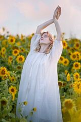 Beautiful blonde girl in a white dress in a field of sunflowers