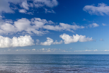 Calm sea beneath bright clouds and blue sky