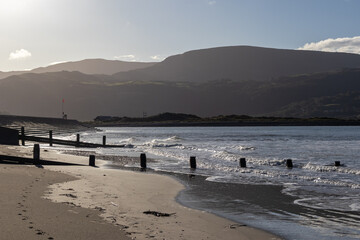 Quiet shoreline with gentle waves and coastal groynes in soft light