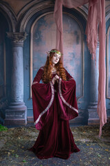 A girl in an elf costume in a studio with fabrics. Medieval decorations