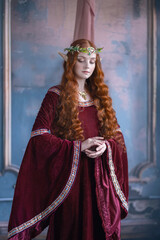 A girl in an elf costume in a studio with fabrics. Medieval decorations