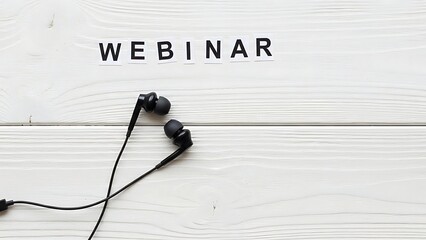 Black earbuds with cord placed on white wooden surface with word WEBINAR webinar