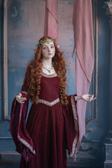 A girl in an elf costume in a studio with fabrics. Medieval decorations