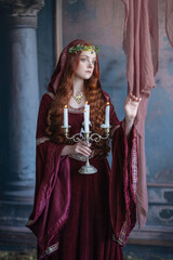 A girl in an elf costume in a studio with fabrics. Medieval decorations