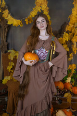 Long-haired girl in a studio among leaves and pumpkins