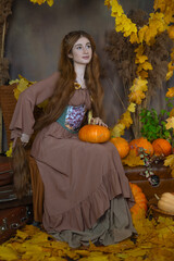 Long-haired girl in a studio among leaves and pumpkins