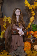 Long-haired girl in a studio among leaves and pumpkins