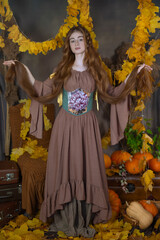 Long-haired girl in a studio among leaves and pumpkins