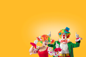 Funny male and female clowns pointing upward at blank copy space. Humorous concept for entertainment, circus themes, promotion, announcements, and playful creative designs.